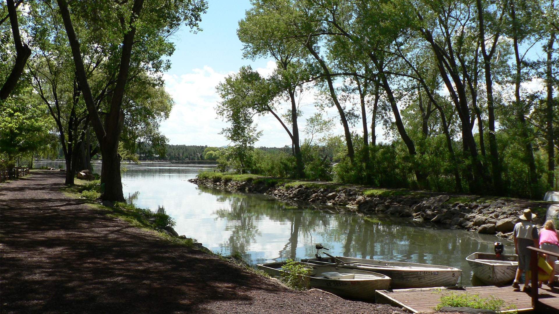 Landscape view of Lakeside, Arizona with boat dock, tree-lined lake shore, and forested hills in the distance.