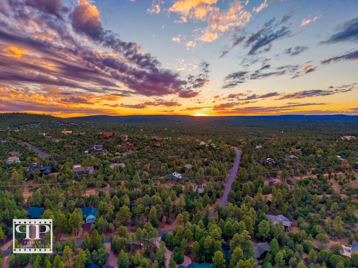 Aerial view of Show Low, AZ at sunset with homes among abundant tree coverage.